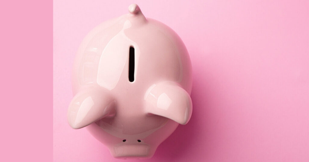 Pink ceramic piggy bank on pink background.