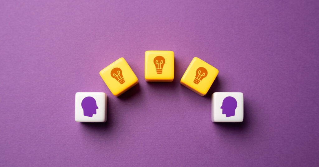 Dice with heads and lightbulbs on purple surface.
