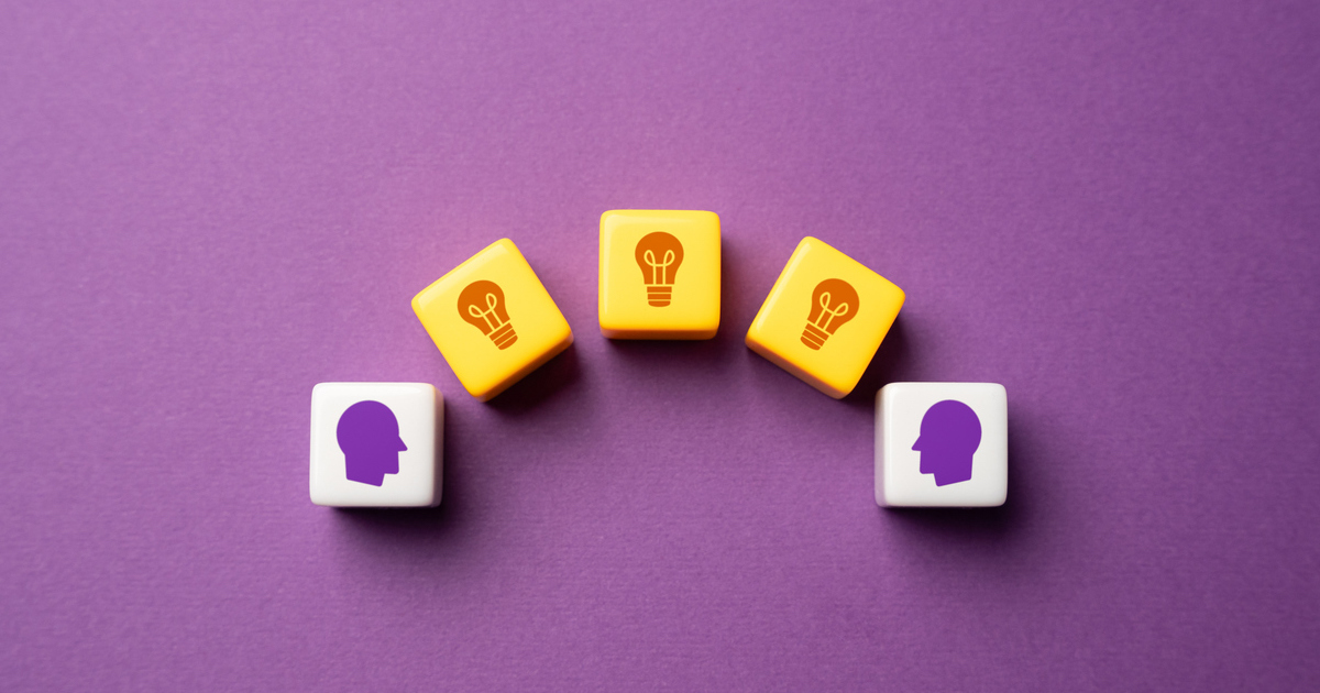 Dice with heads and lightbulbs on purple surface.