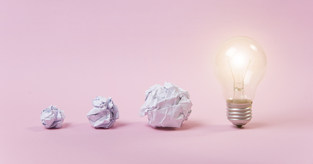 Crumpled paper balls and lit light bulb