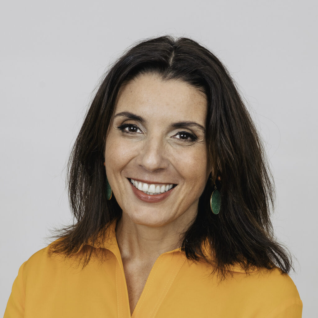 Smiling woman in orange shirt with earrings.