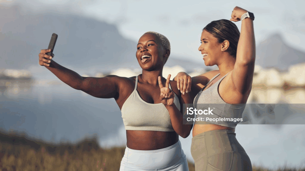 Two women taking selfie by lake, joyful moment.