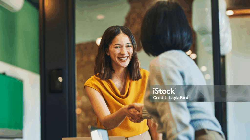 Women shaking hands and smiling in office setting