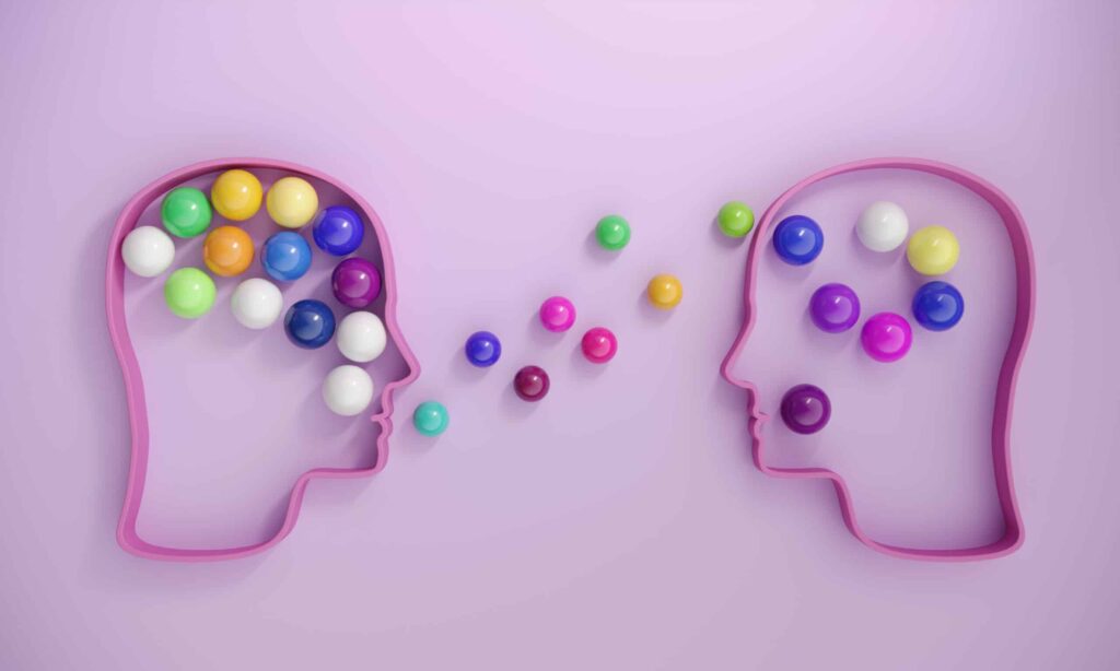 Human heads includes lots of multi colored spheres, symbolizing communication concepts.