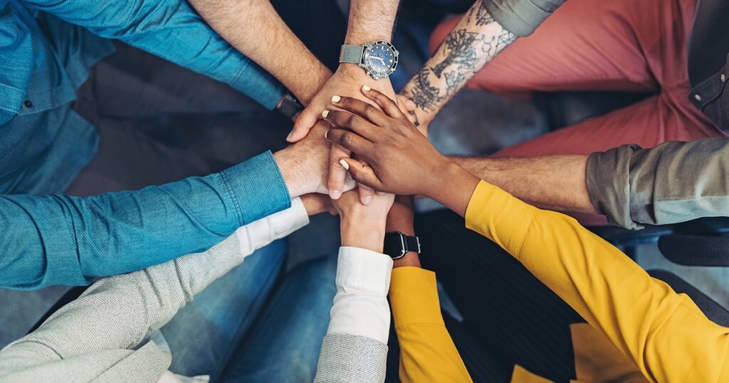 Diverse group stacking hands in unity