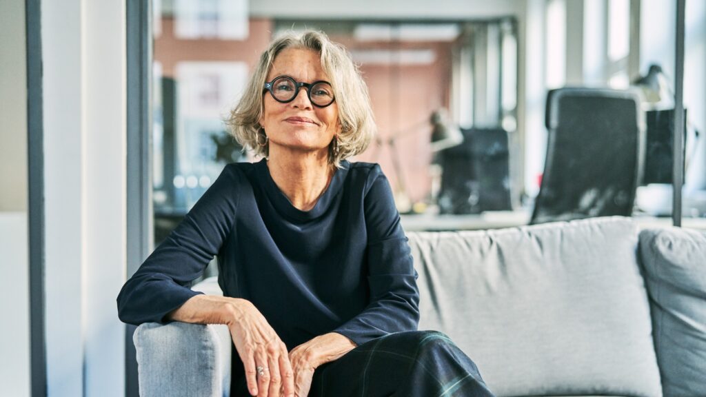 Smiling person with glasses sitting on couch